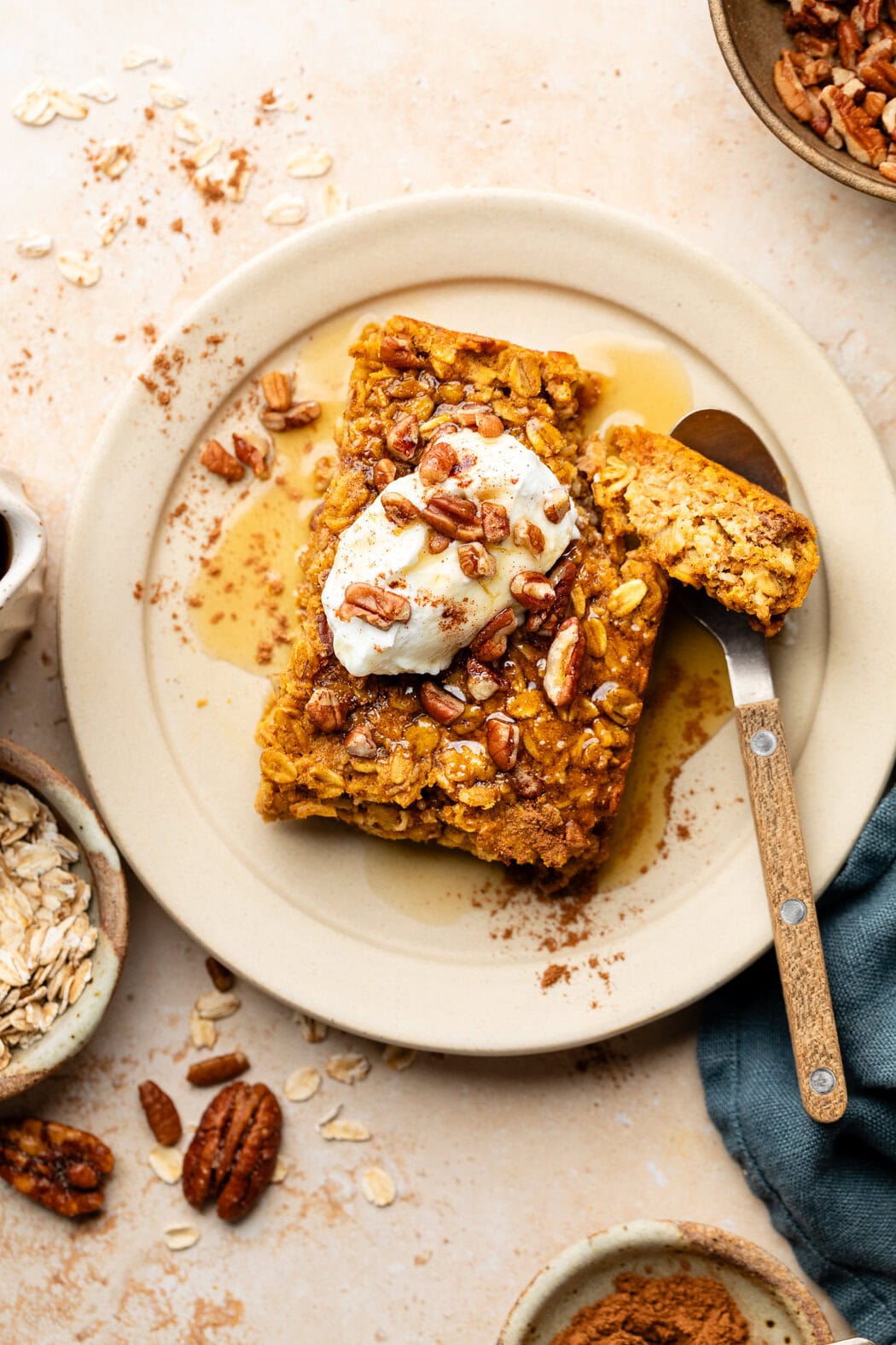 Overhead view of a plate of Pumpkin Baked Oatmeal topped with whipped cream and drizzled with maple syrup. 