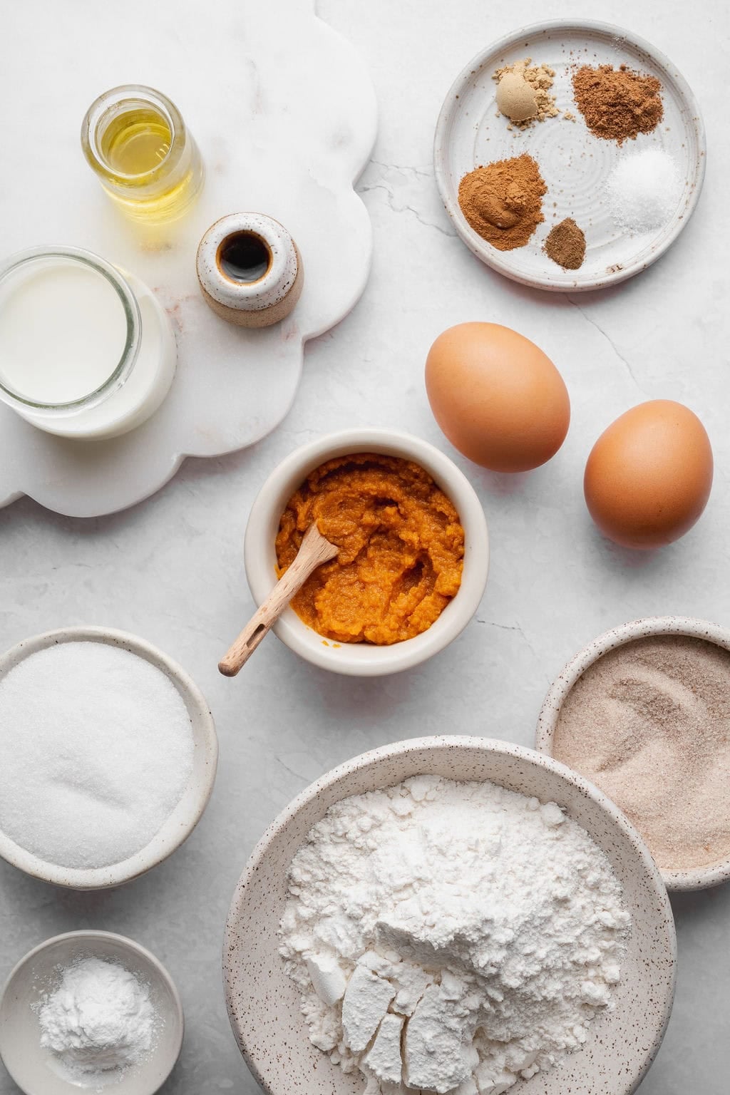 Ingredients to make baked pumpkin donuts with a cinnamon sugar coating.