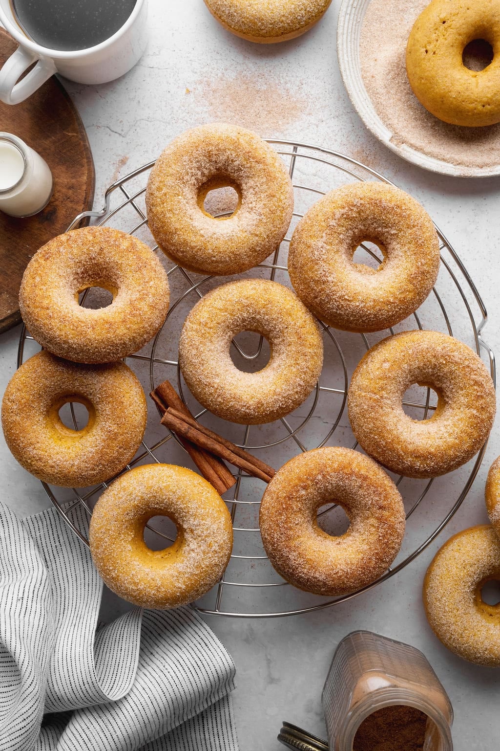 Pumpkin donuts coated in cinnamon sugar on a wire rack.