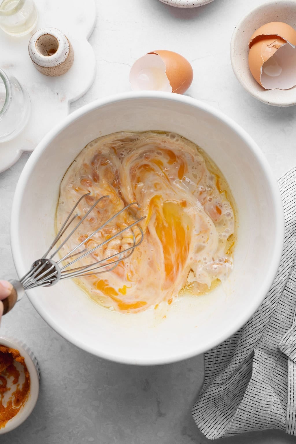 Wet ingredients for pumpkin donuts being whisked in a bowl.