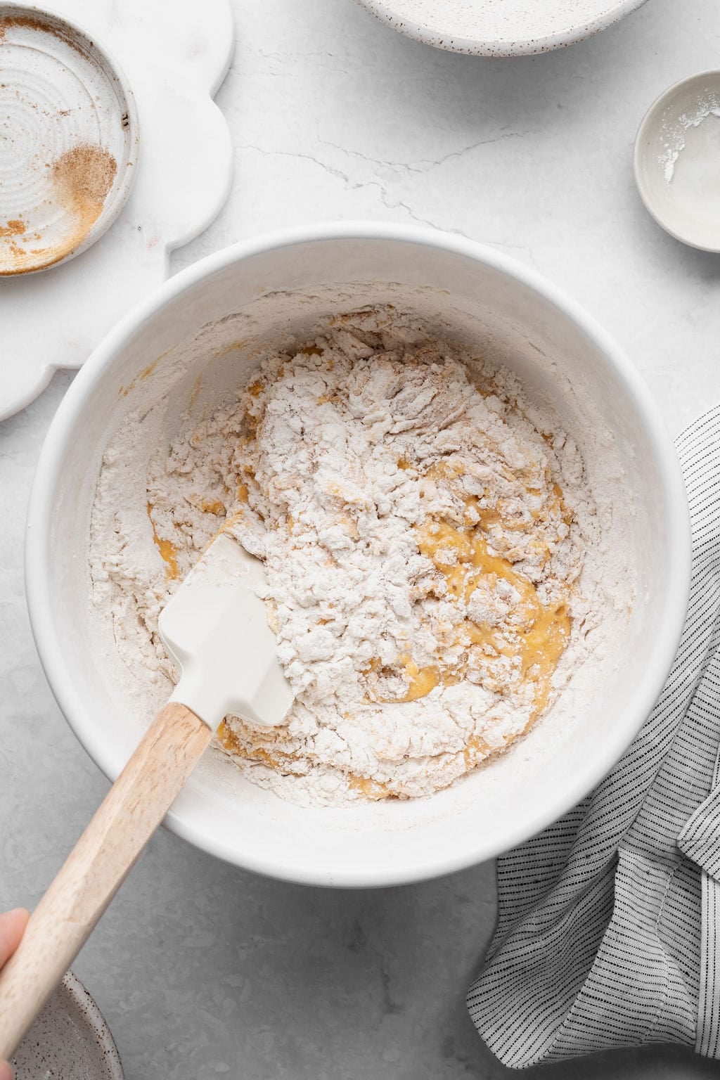 Dry ingredients being folded into wet ingredients for pumpkin donut batter.