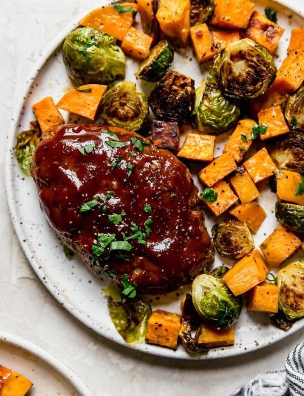 Overhead view stone plate filled with bbq mini meatloaf and roasted vegetables