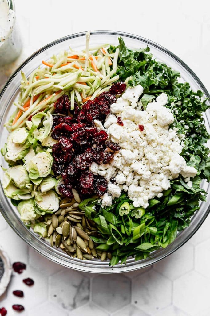 Sweet Kale Salad ingredients in a large clear bowl.