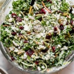 Sweet kale salad tossed in dressing in a clear glass bowl