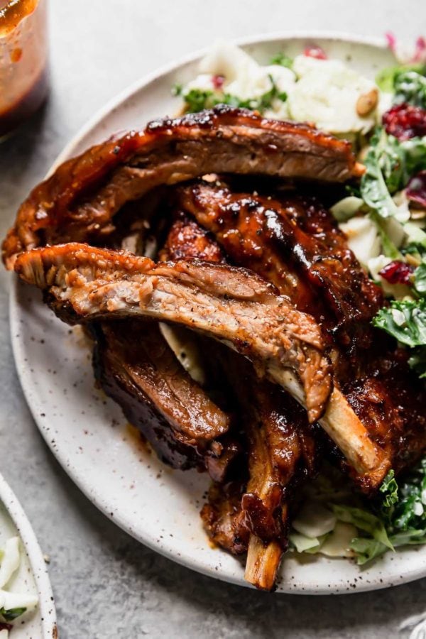 A hefty stack of bbq instant pot pork ribs on a speckled plate with kale salad on the side