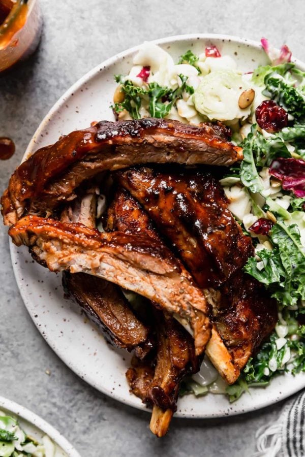 BBQ baby back ribs on a speckled plate with a kale salad