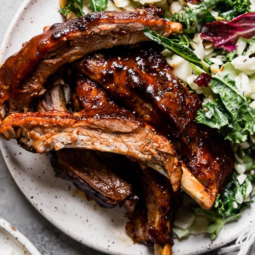Instant Pot Baby Back Ribs on a speckled plate with kale salad on the side
