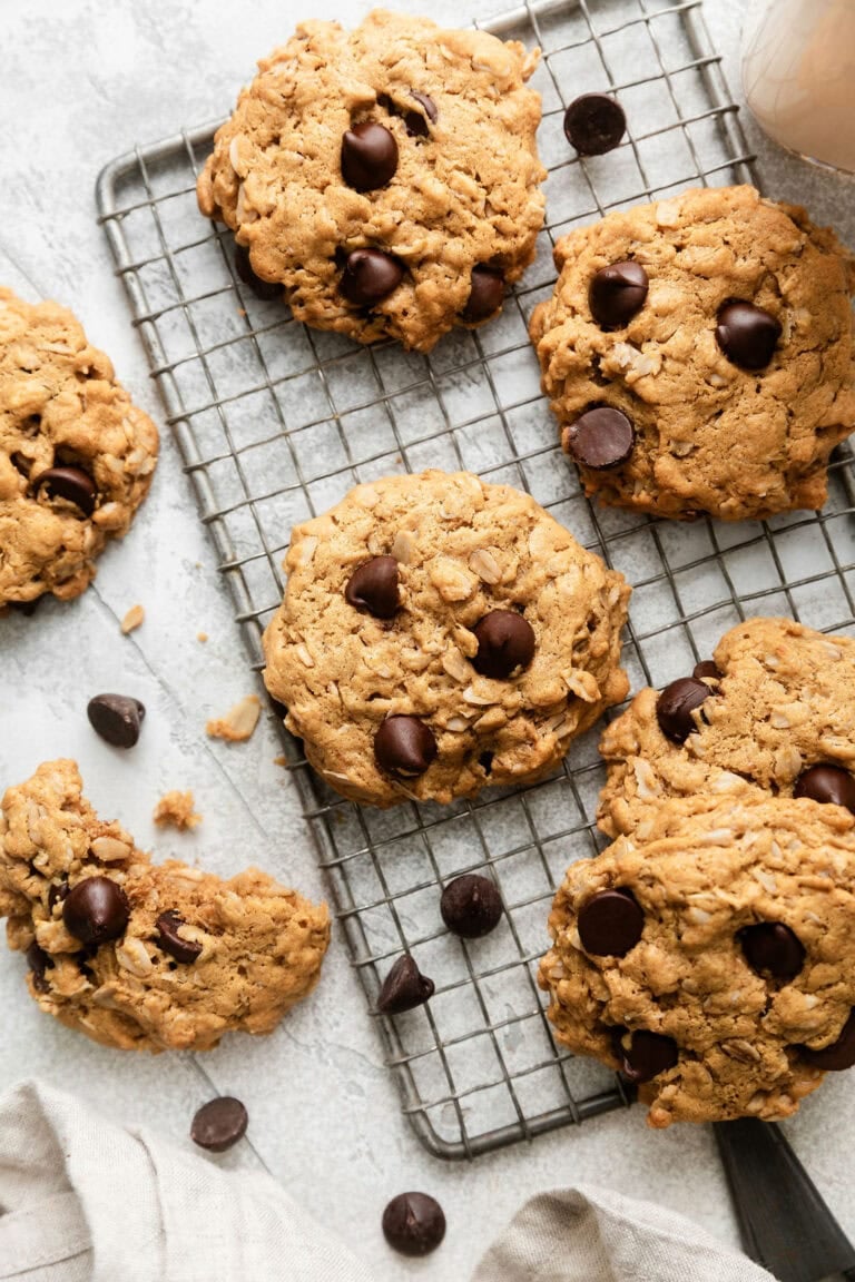 Overhead view of a cooking rack filled with freshly baked peanut butter and oatmeal cookies studded with chocolate chips.