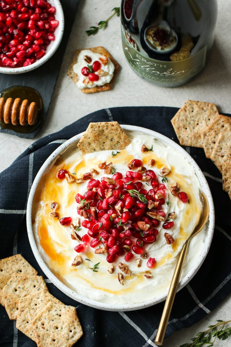Honey Whipped Goat Cheese with pomegranate seeds on top and crackers on the side. 