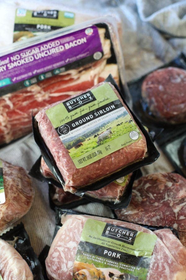 A pile of frozen packaged assorted meat with ground sirloin from Butcher Box in focus