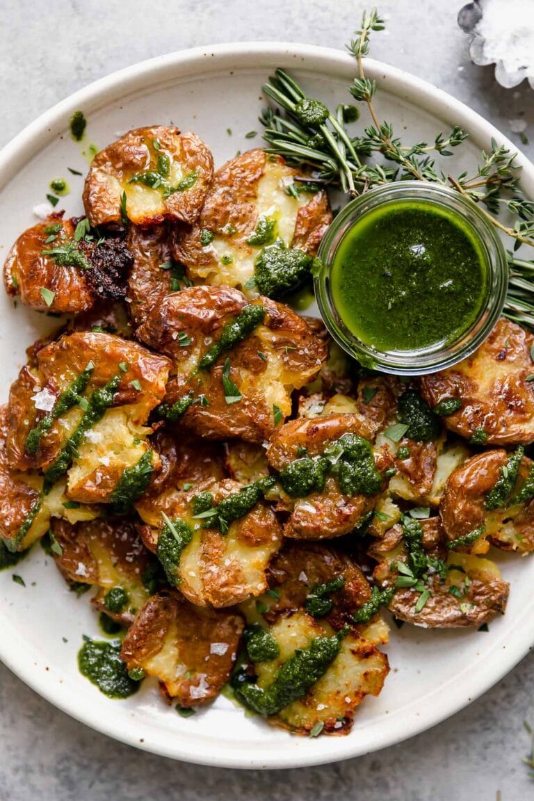 Overhead view of Crispy Smashed Potatoes drizzled with green sauce and topped with flakey salt.