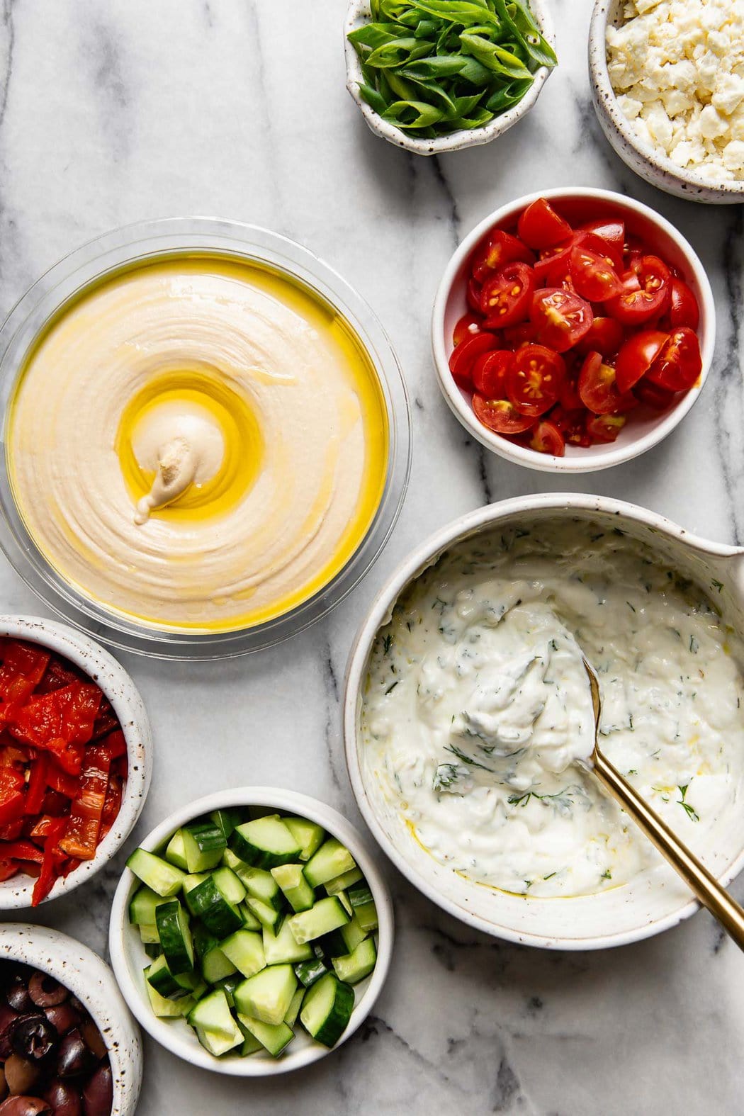 All ingredients for a layered Greek hummus arranged together