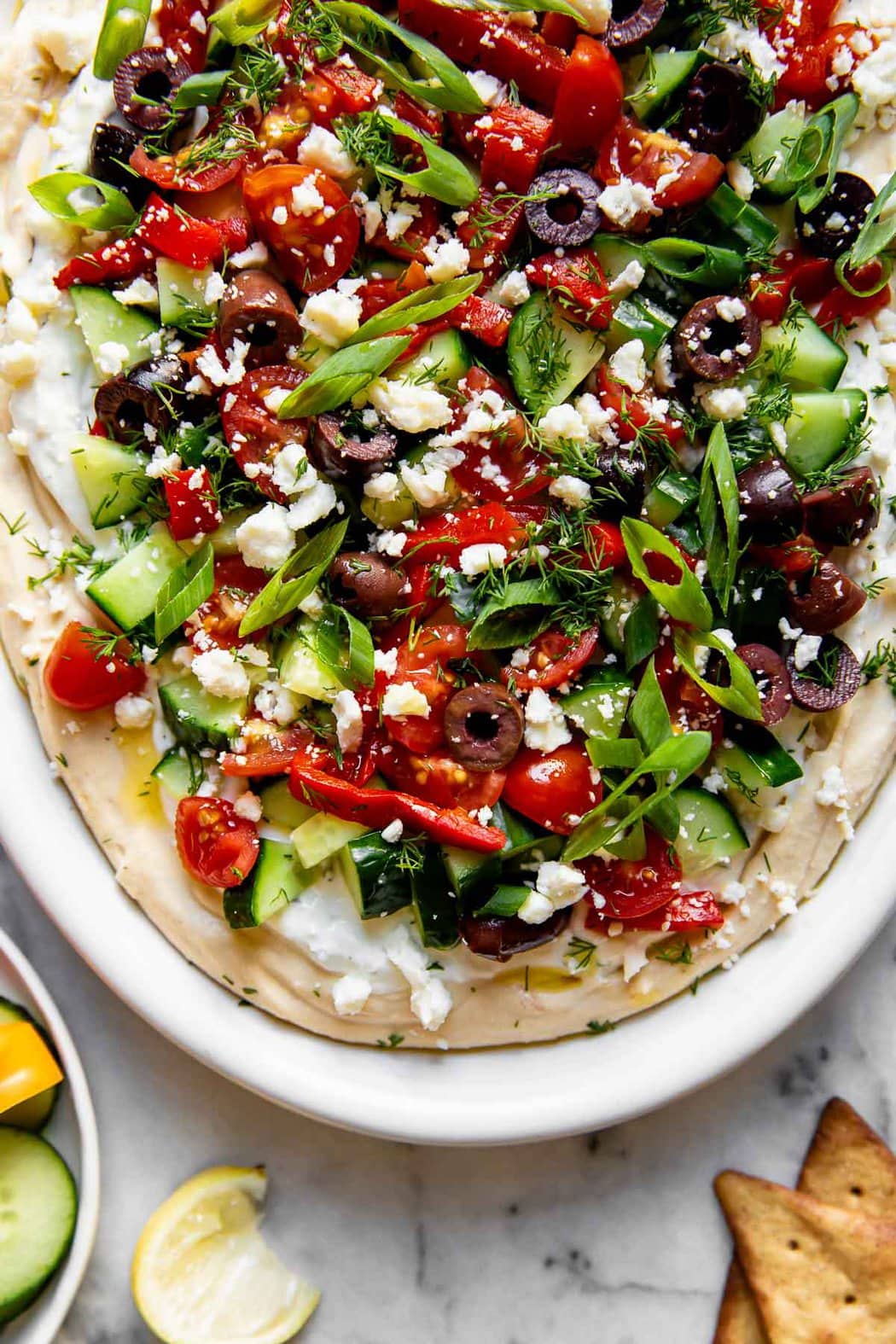 Close up view layered Greek Hummus Dip on white serving platter