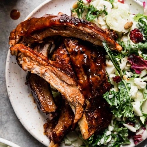 Instant Pot baby back ribs coated in sauce on plate with side salad