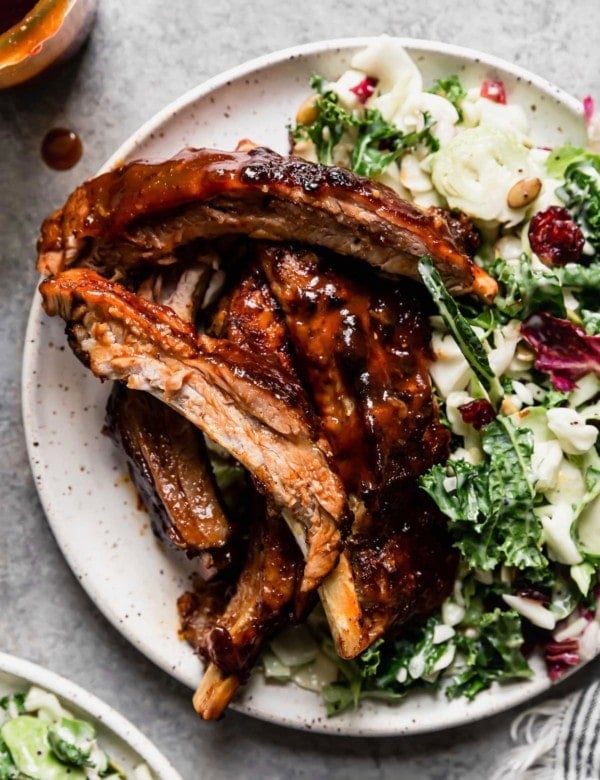 Instant Pot baby back ribs coated in sauce on plate with side salad