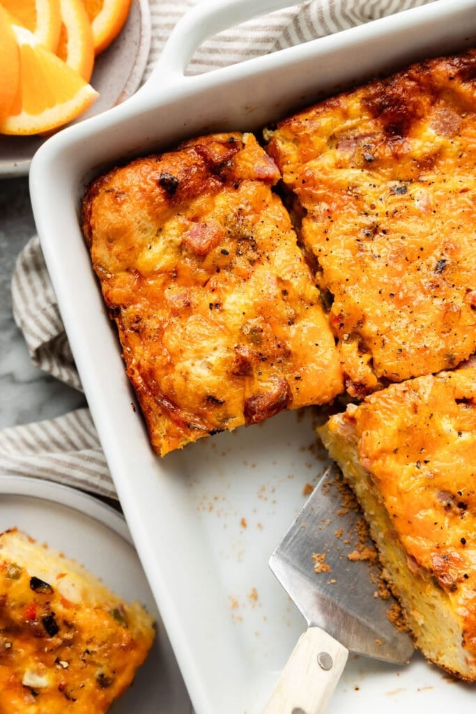 Close up view breakfast casserole in white baking dish cut into squares