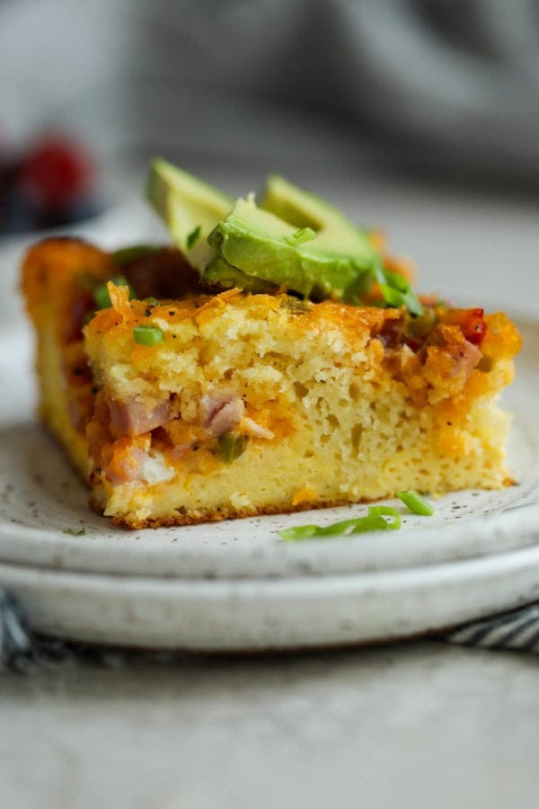 A close up view of pancake-based egg breakfast casserole to show the great texture. Topped with sliced avocado.
