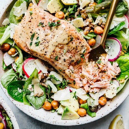 Overhead view of salmon caesar salad grain bowl in a speckled bowl