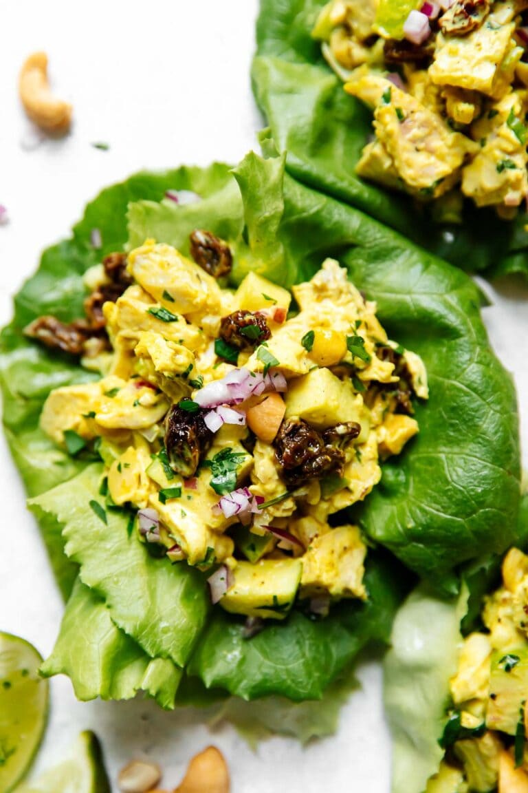 Overhead view of a lettuce wrap filled with the best curry chicken salad topped with red onion. 