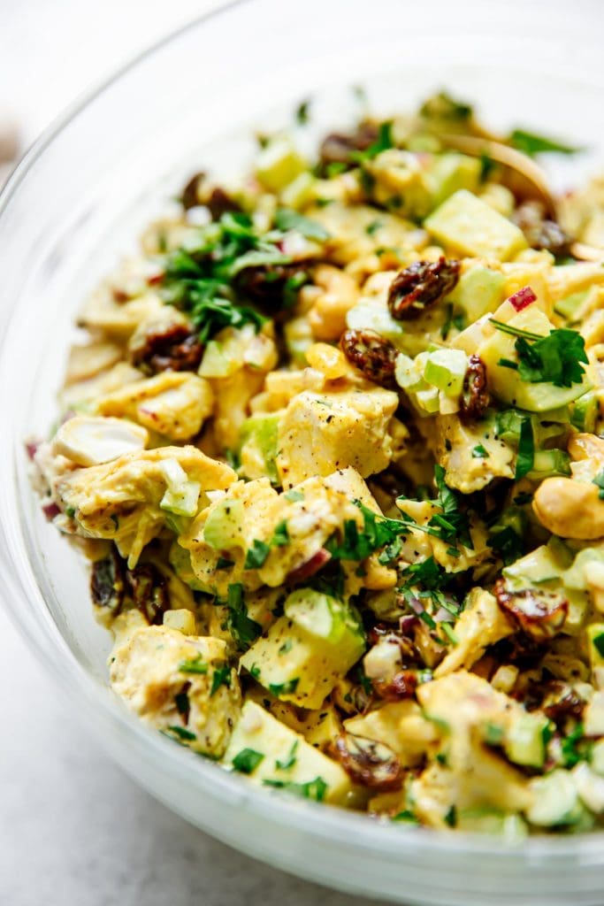 All ingredients for curry chicken salad mixed together in a bowl ready for serving.