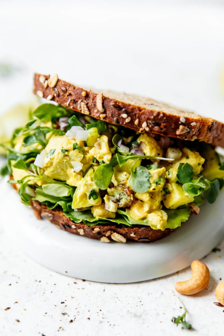 Curry chicken salad sandwich with lettuce and sprouts and cashews