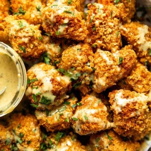 Overhead view breaded chicken nuggets in pile with honey mustard sauce drizzled over top