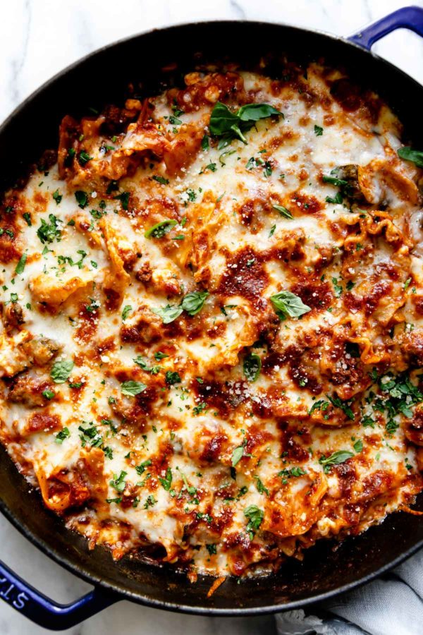 A blue cast iron skillet filled with cooked easy skillet lasagna topped with golden bubbly mozzarella cheese