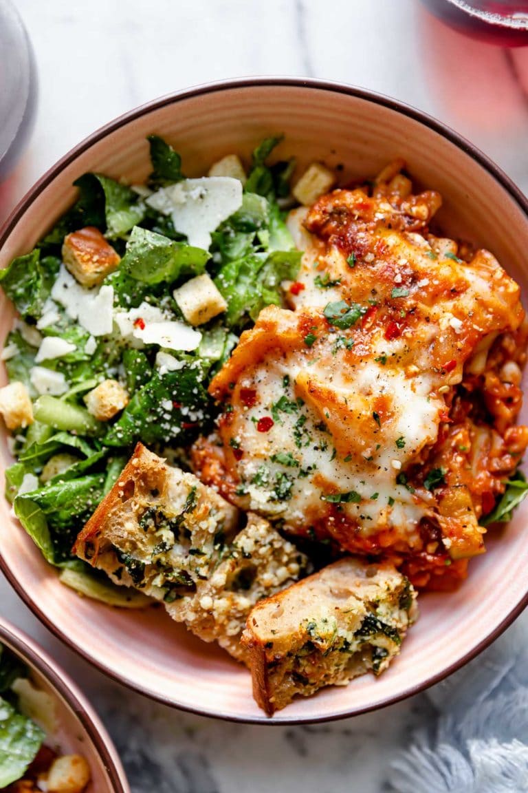 Overhead view of a plate of easy skillet lasagna with a side salad topped with parmesan cheese. 