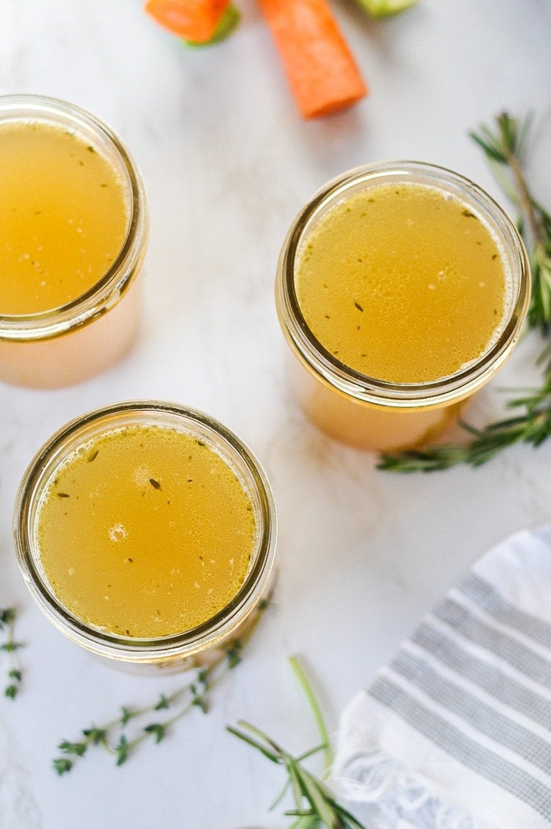 Overhead view of Instant Pot bone broth in mason jars with rosemary around the jars