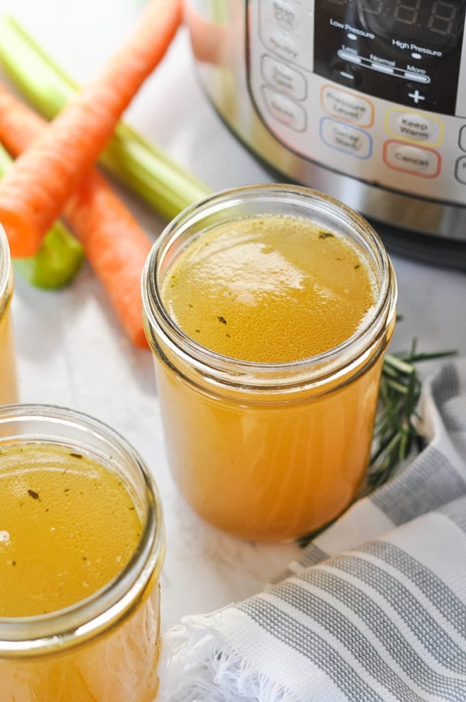 Homemade bone broth in a mason jar in front of an Instant Pot