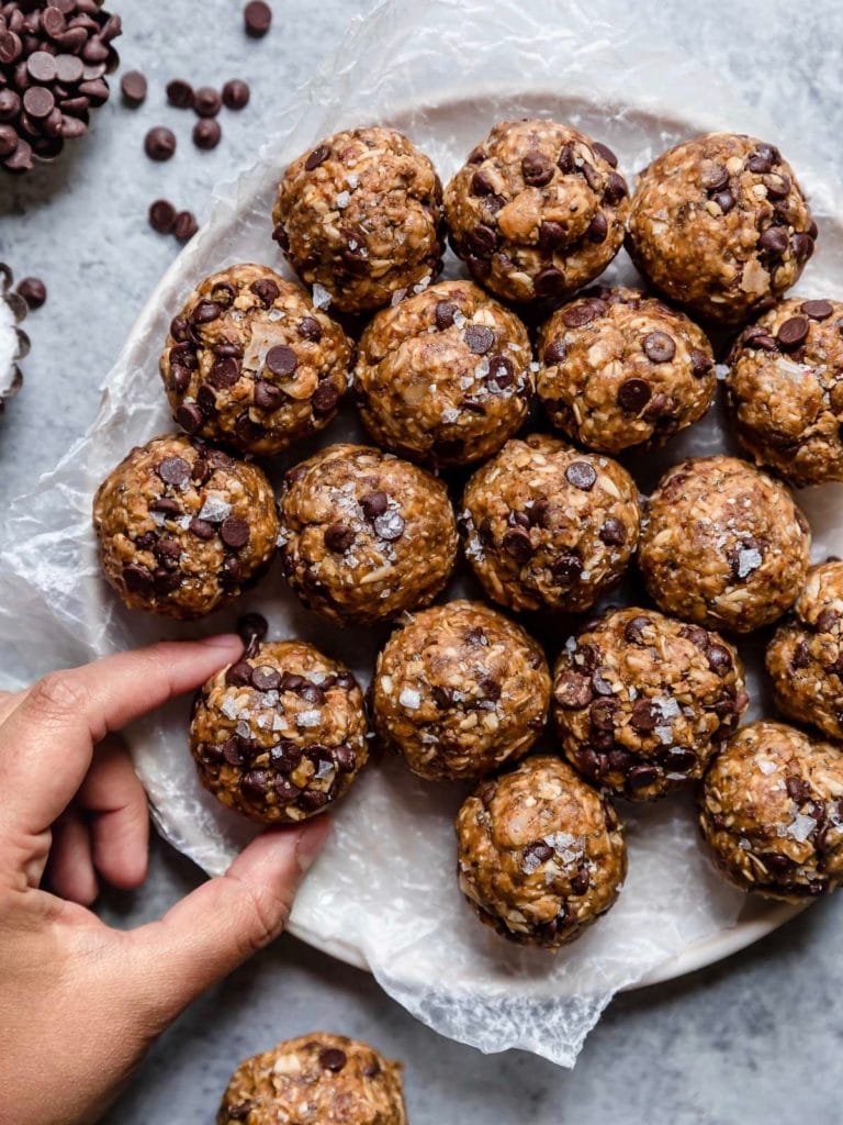 Close up view of a plate of peanut butter chocolate chip energy bites topped with flakey sea salt. 