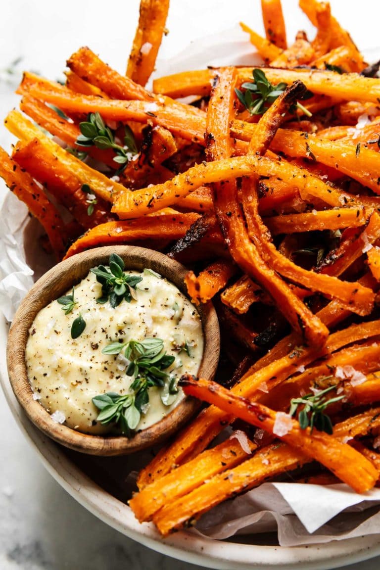Baked carrot fries on tray with small wooden bowl filled with dijon-thyme aioli