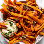 A large bowl of oven baked carrot fries with a side of dijon-thyme aioli