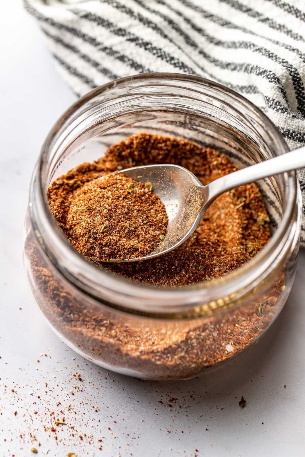 Overhead view of a small mason jar filled with Homemade Taco Seasoning and a spoon in the jar. 