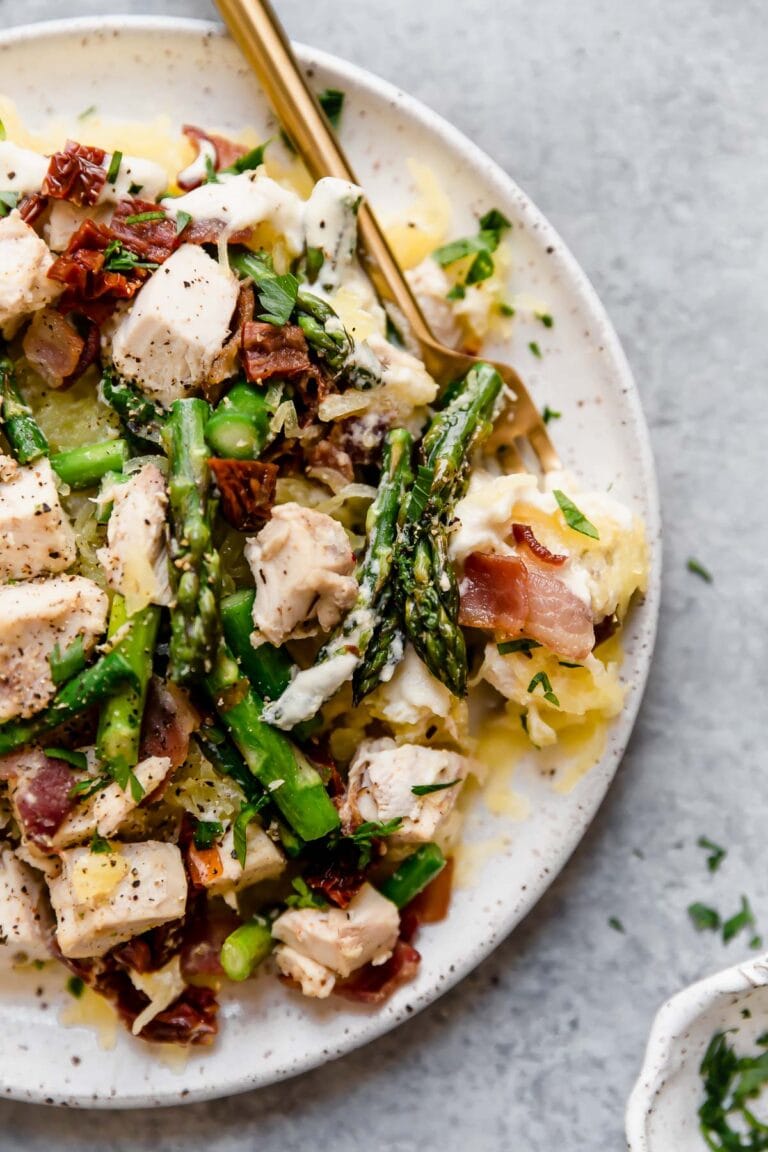 Close up overhead view creamy chicken spaghetti squash with bacon and asparagus on a stone plate.