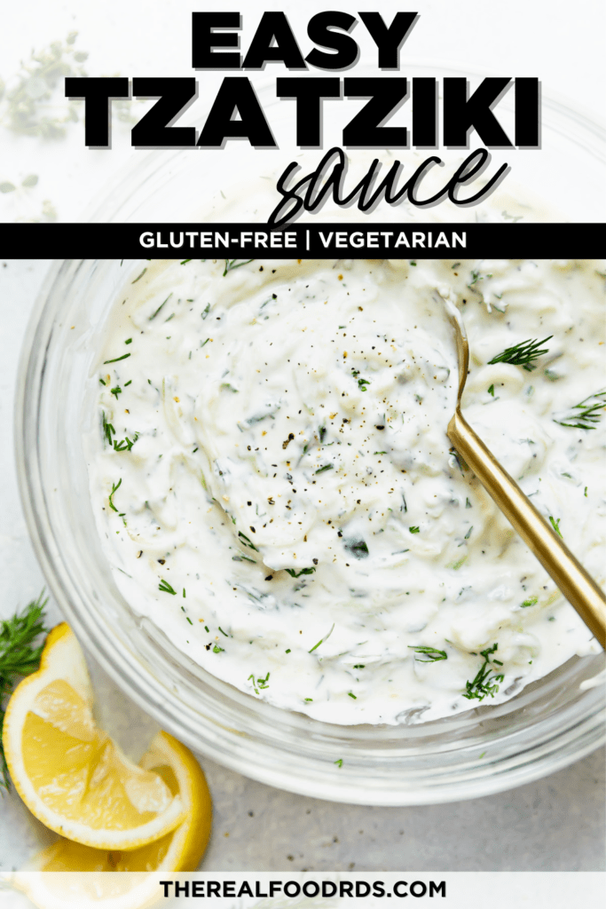 Creamy and lemony homemade Tzatziki sauce in a glass bowl being stirred with a gold spoon.