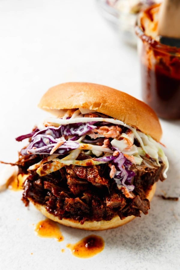 A brisket sandwich overfilled with juicy and tender beef brisket and homemade coleslaw in a large bun