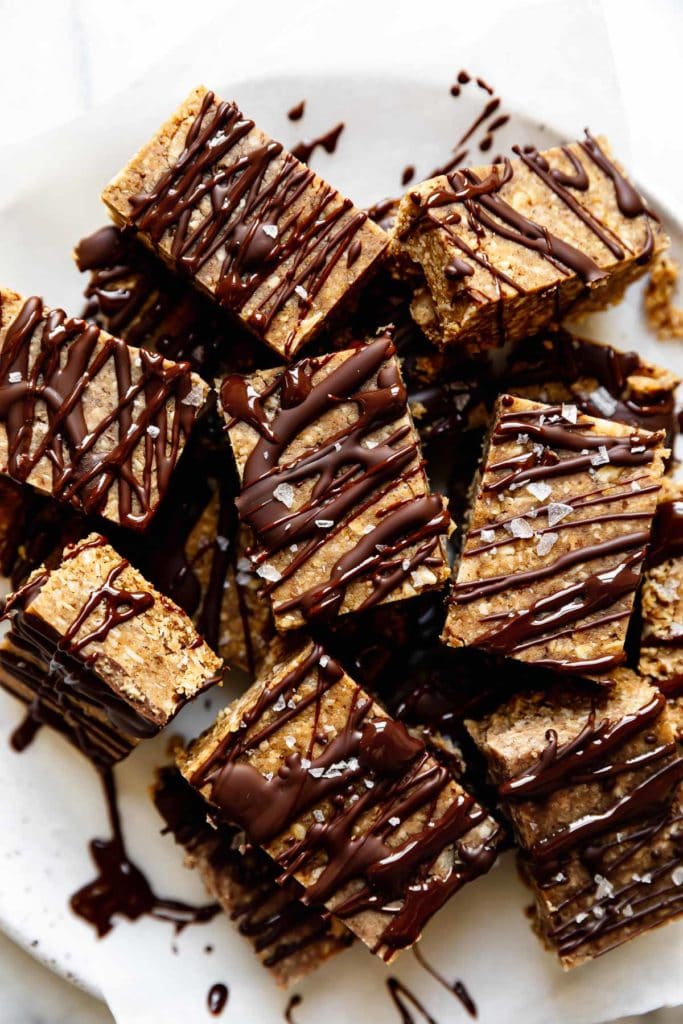 A plate full of mini peanut butter protein bars drizzled with chocolate and sea salt flakes.
