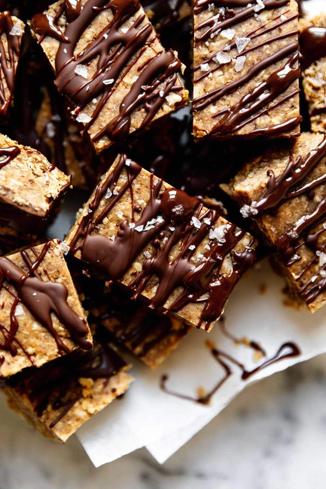 A close up view of mini peanut butter bars drizzled with dark chocolate and sprinkled with sea salt flakes.