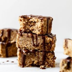 Three mini peanut butter protein bars stacked on each other drizzled with dark chocolate