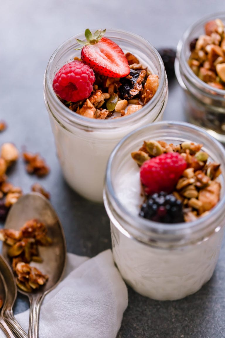 Overhead view of jars of yogurt topped with paleo granola and fresh berries. 