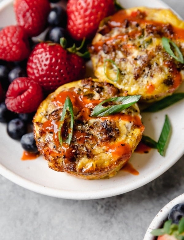 Side view of egg muffins on a plate with fresh berries