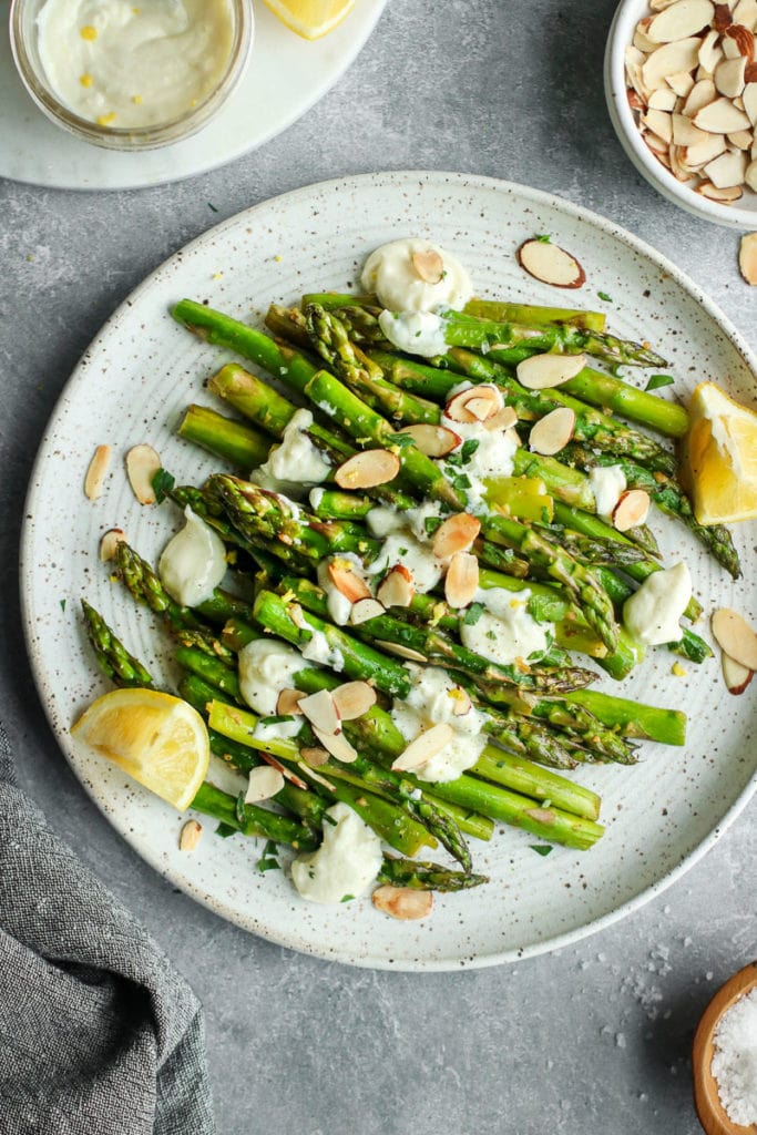 Sautéed Asparagus on a speckled plate topped with lemon goat cheese sauce and toasted almonds. 