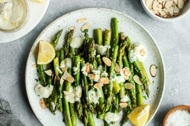 Sautéed asparagus on stone plate drizzled with goat cheese sauce and sliced almonds