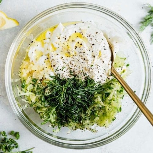 All ingredients for homemade Tzatziki sauce in a glass mixing bowl