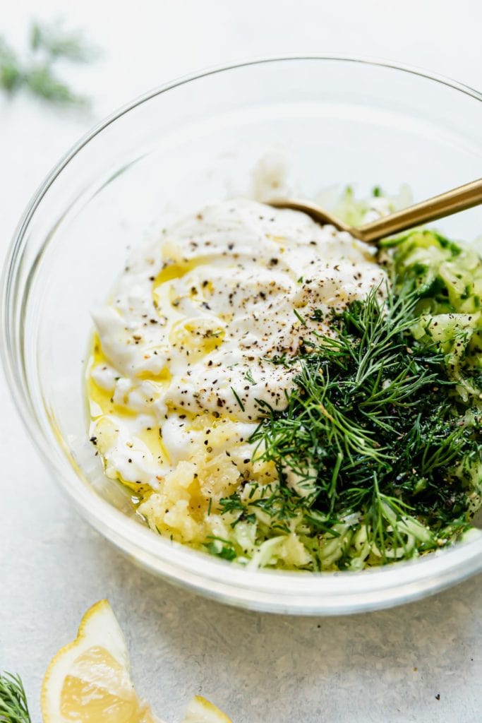 All ingredients for homemade Tzatziki sauce in a glass mixing bowl