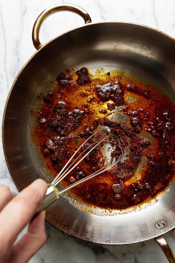 Avocado oil and Mexican spices in a skillet being whisked together