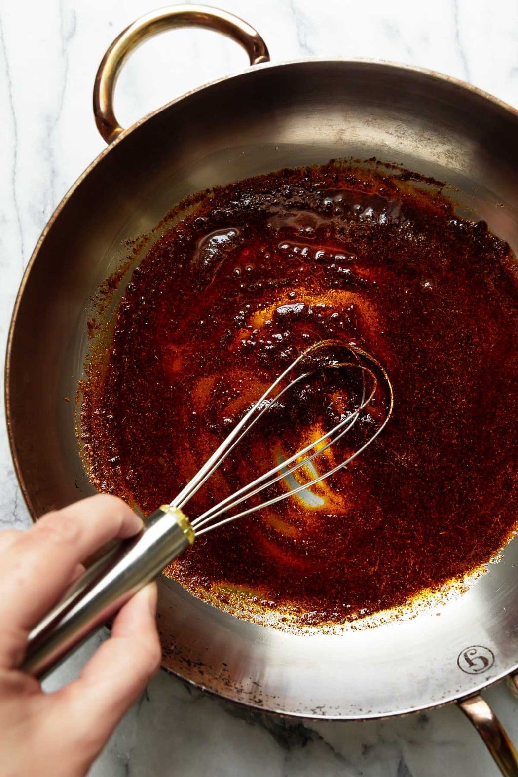 Enchilada sauce being made in a skillet with a whisk