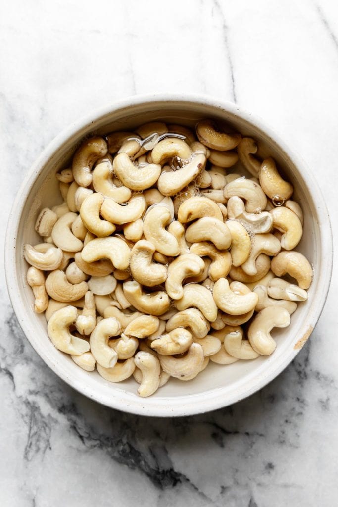 Raw cashews soaking in a bowl of water