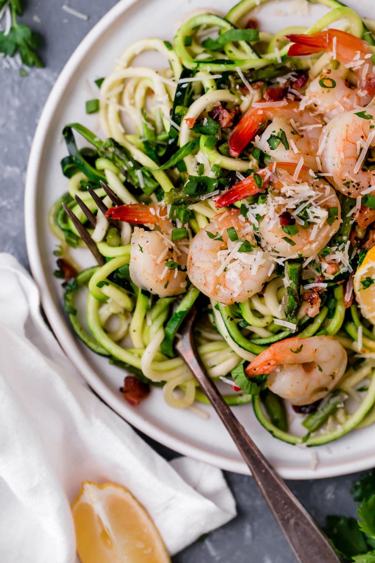 Zucchini pasta carbonara with shrimp on a plate, a fork on top.